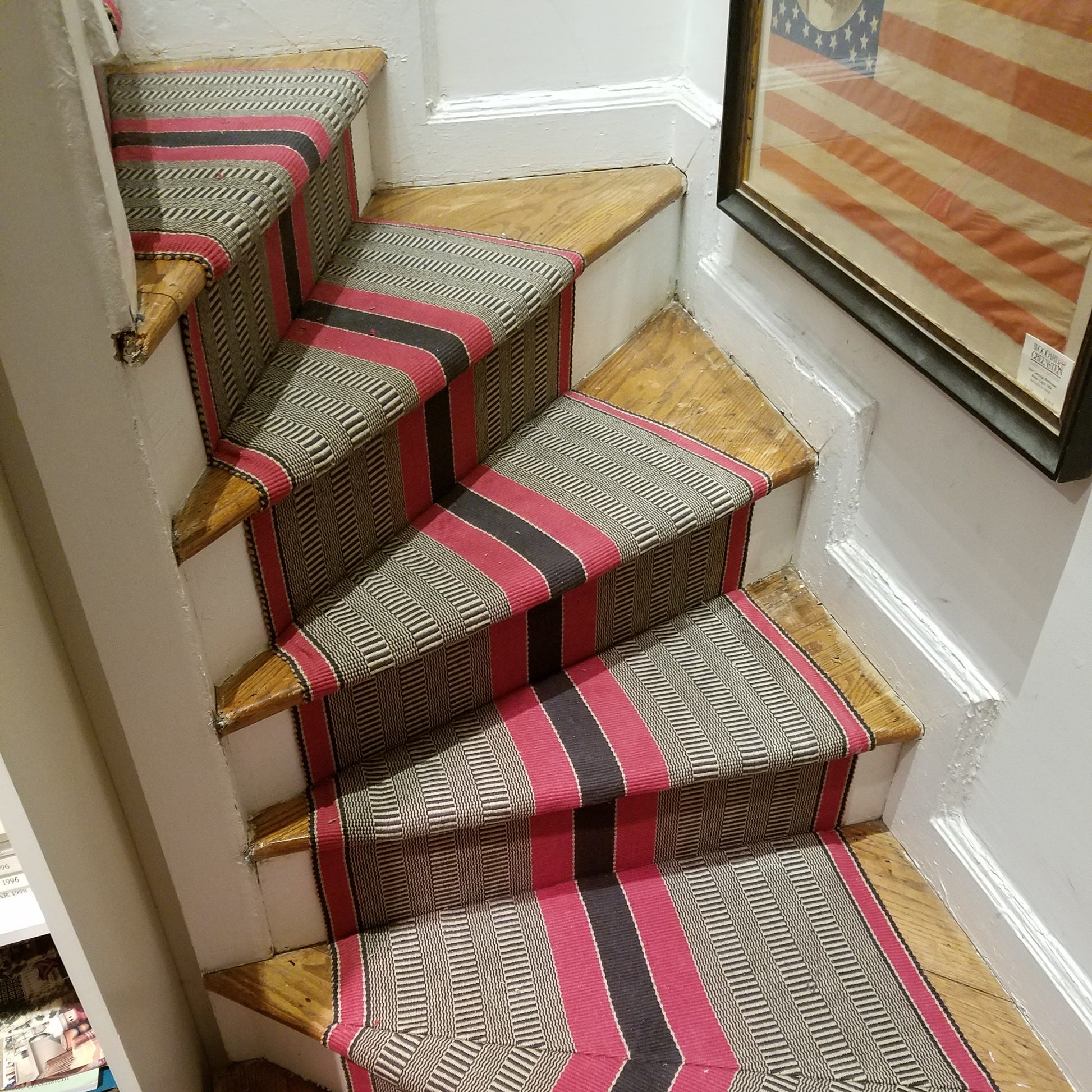 Bold red and black central stripes with natural and charcoal special weave background with red stripes on each edge. Shown here installed on a curved staircase with pie shaped steps and mitered corners.
